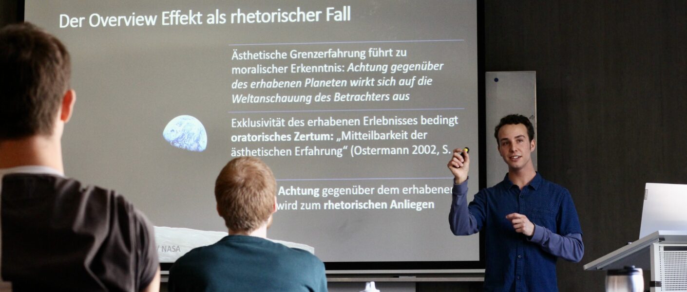 Hagen Wagner präsentiert am 21. April 2023 im Brechtbau seine Bachelorarbeit zum Thema Overview Effekt als rhetorischer Fall