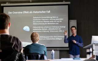 Hagen Wagner präsentiert am 21. April 2023 im Brechtbau seine Bachelorarbeit zum Thema Overview Effekt als rhetorischer Fall